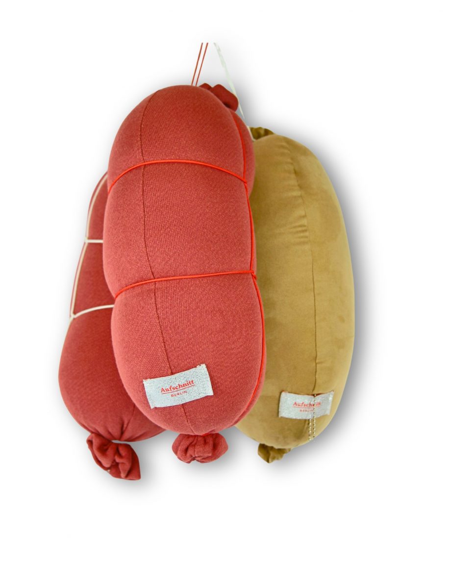 Gemütliches Reisekissen und Nackenkissen von Aufschnitt Berlin in Form eines Bockwurstkissen in orange für Reisen und unterwegs.